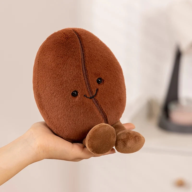Brown kawaii plush toy resembling a bean held in a hand against a neutral background