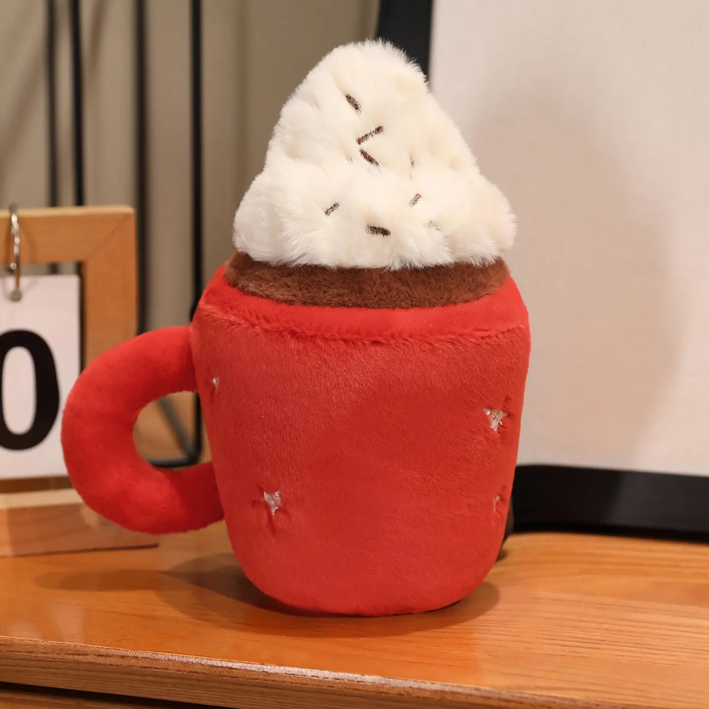 Red kawaii plush mug with a white fluffy top on a wooden surface