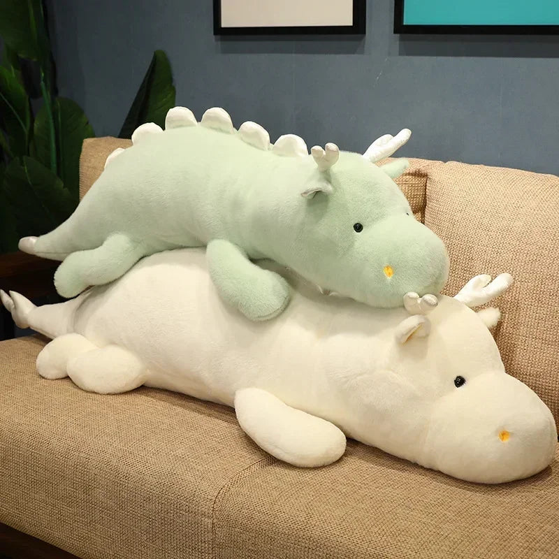 Two kawaii plush dragon toys on a brown couch against a gray wall.