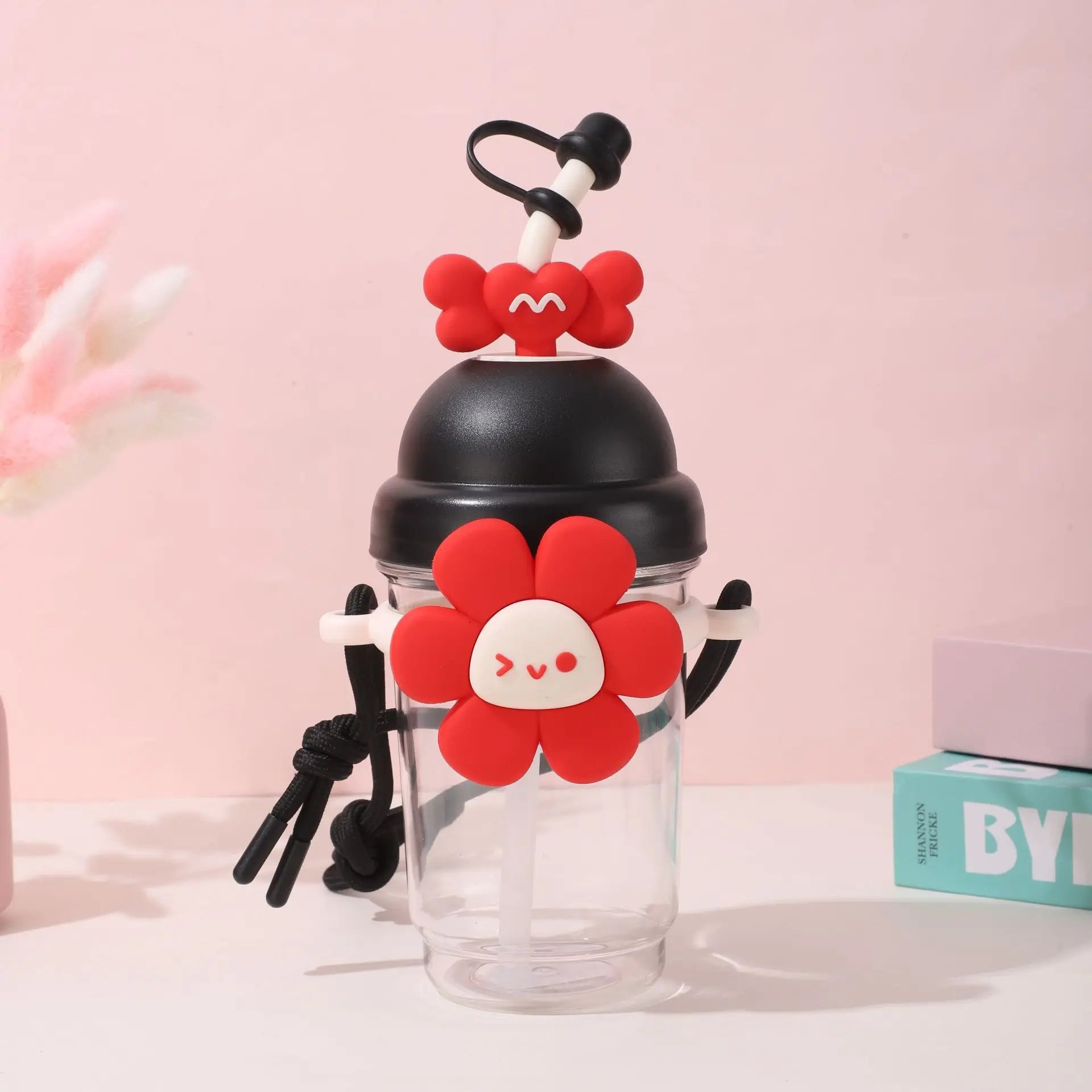 Clear tumbler with Kawaii red flower design and black lid on a pink background