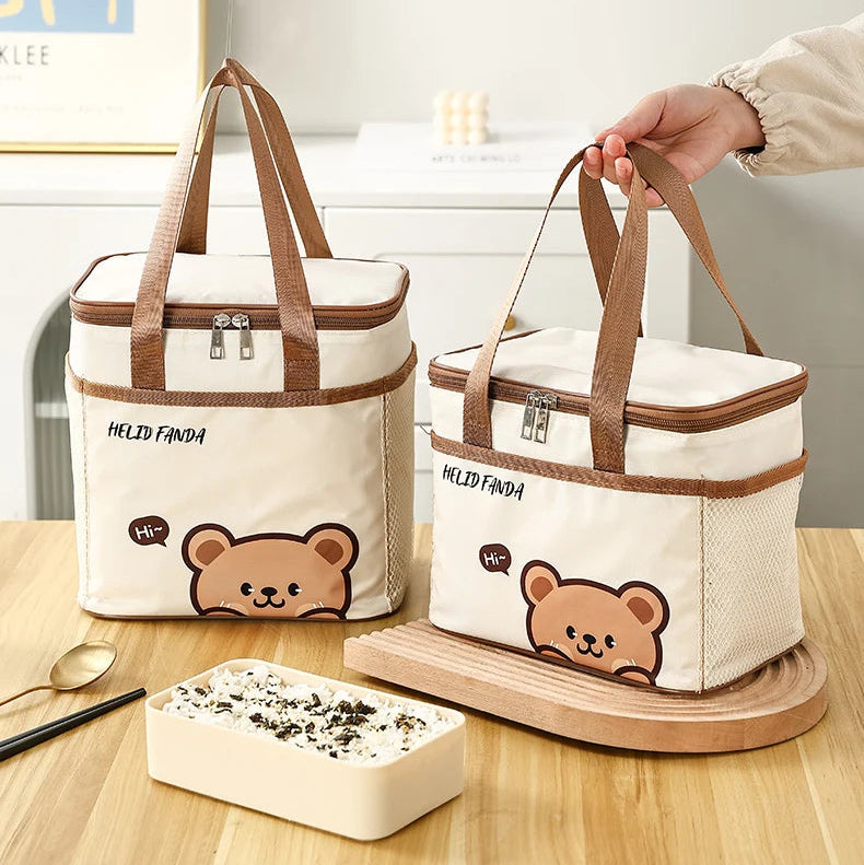 Two kawaii bear-themed cooler bags on a wooden surface with a small container of food.