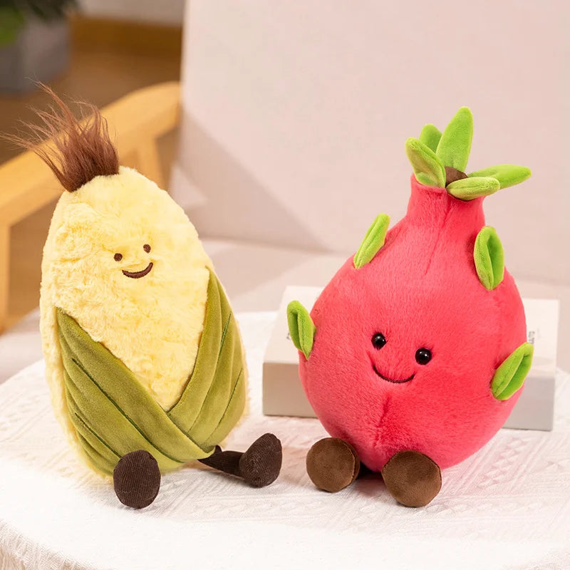 Two plush kawaii toys resembling a yellow fruit with green leaves and a pink fruit with green leaves on a white surface.