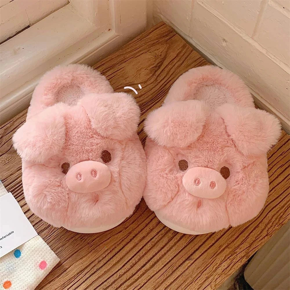 Pair of pink pig-shaped kawaii slippers on a wooden floor.