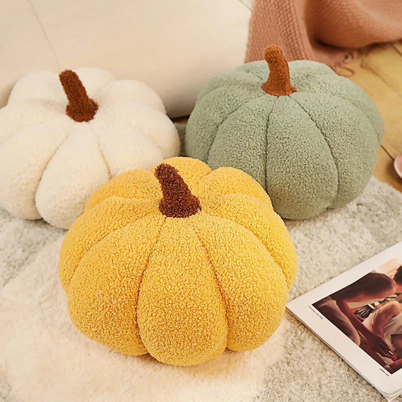 Three plush pumpkin-shaped kawaii cushions in yellow, green, and white on a soft surface.