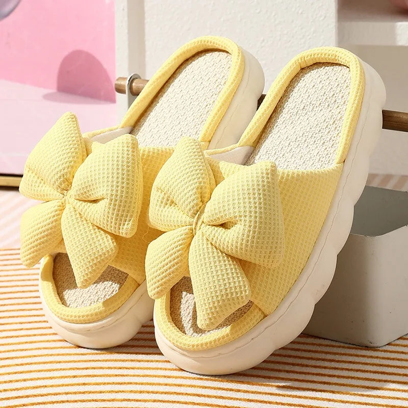Yellow slippers with large kawaii bows on a striped surface