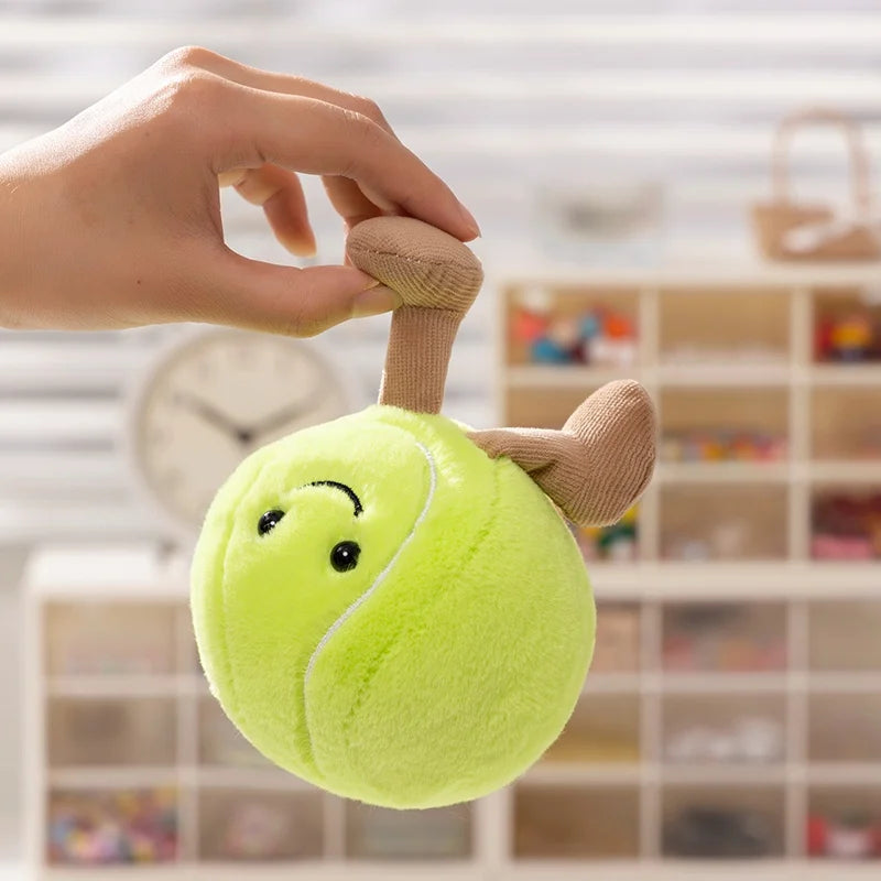 Plush kawaii toy resembling a tennis ball with antlers held by a hand against a blurred indoor background.