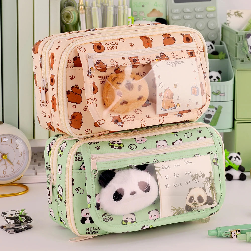 Two cartoon-themed kawaii pencil cases with plush toys inside on a desk.