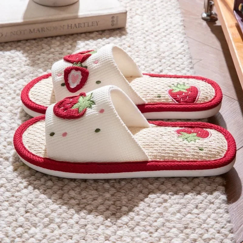 Pair of slippers with strawberry kawaii design on a textured surface