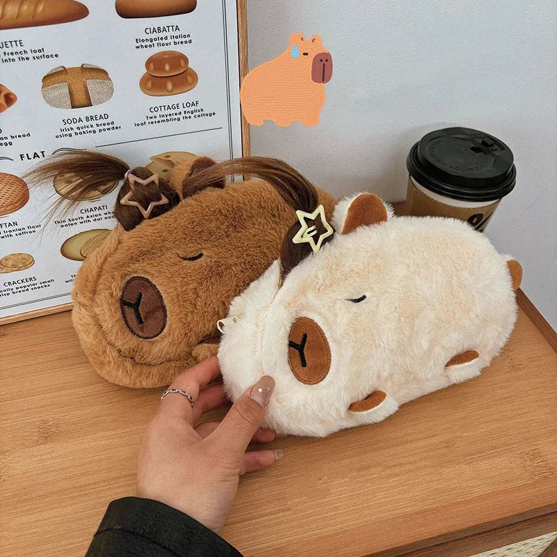 Two kawaii plush toys resembling horses on a wooden surface with a hand touching one of them.