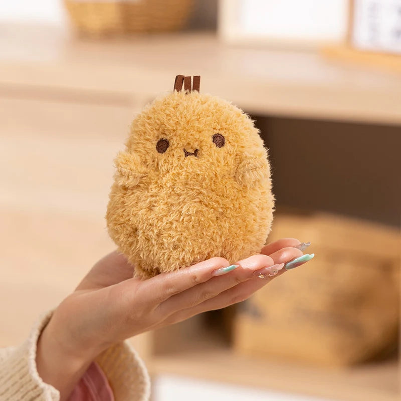 Plush kawaii toy resembling a round, yellow creature held in a hand with a blurred background