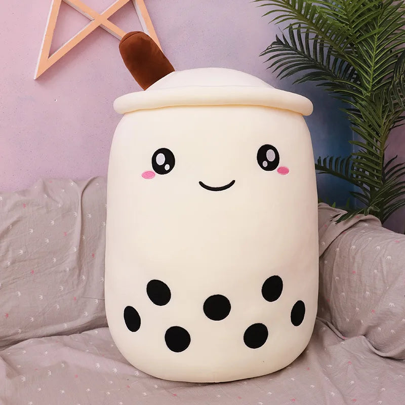 Cute kawaii plush toy resembling a bubble tea cup with a smiling face on a bed.