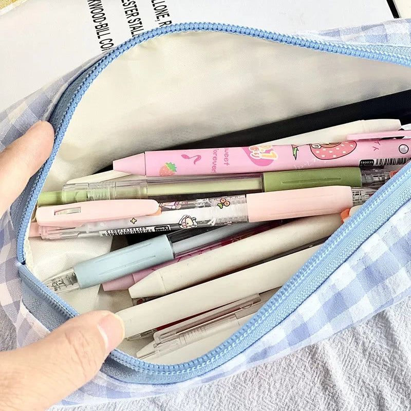 Pouch filled with colorful pens and pencils on a kawaii checkered fabric background
