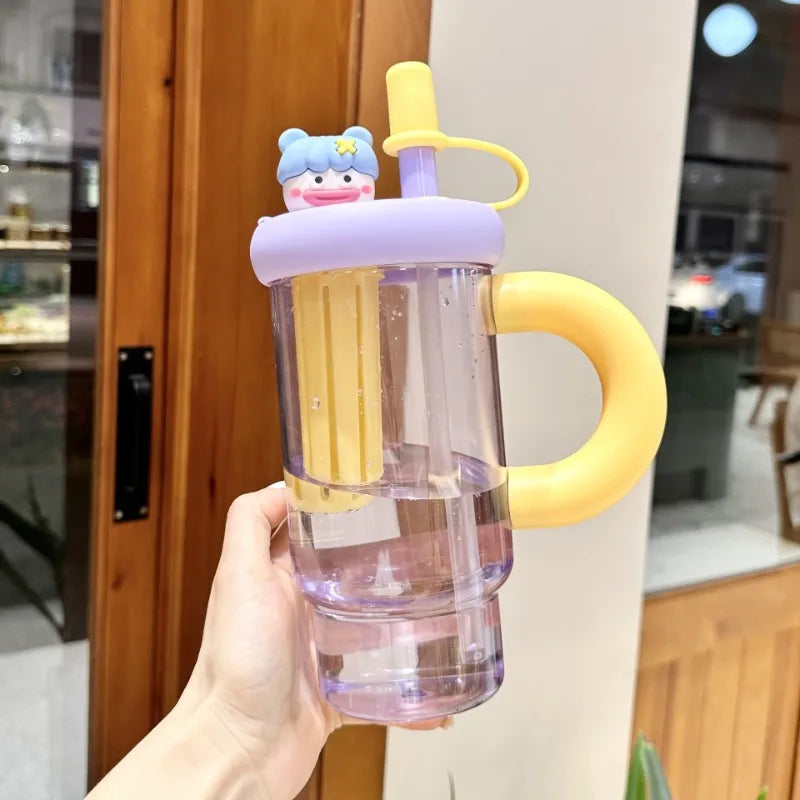 Clear tumbler with Kawaii cartoon character lid held by a hand in an indoor setting