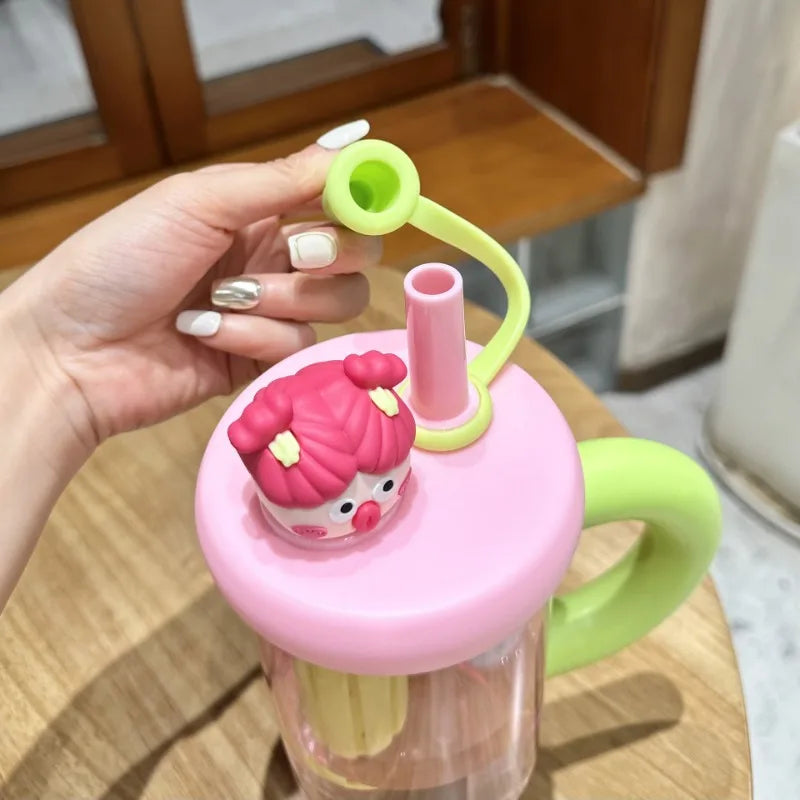 Pink and green water bottle with a Kawaii cartoon character on a wooden surface