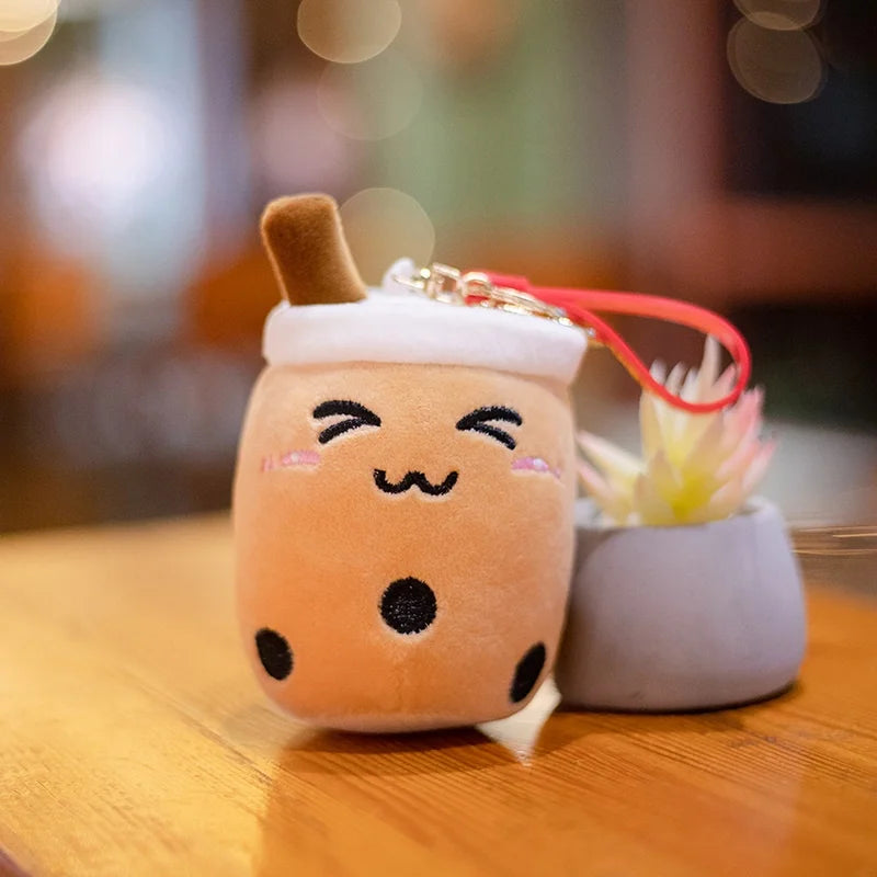 Kawaii plush toy resembling a bubble tea with a keychain on a wooden surface.