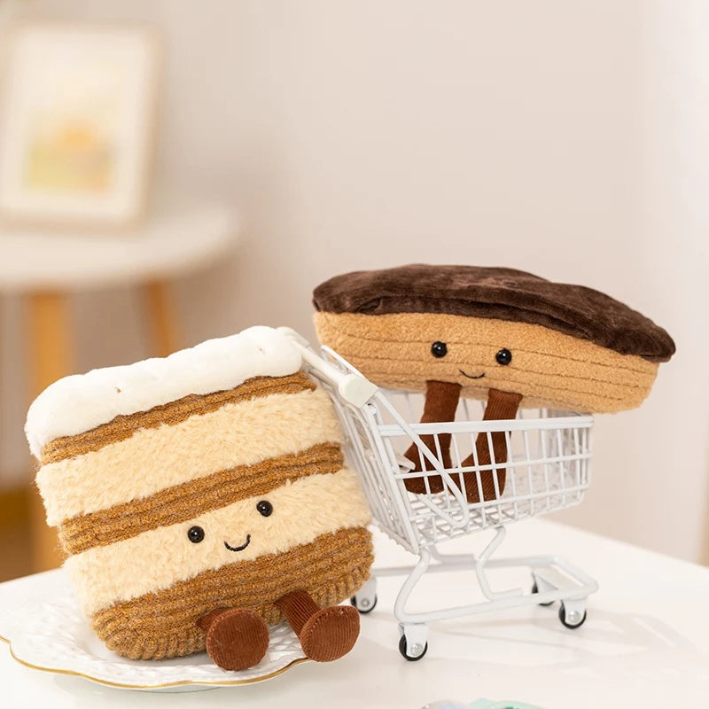 Plush kawaii toy resembling a slice of cake with a plush toy wearing a hat pushing a small shopping cart.