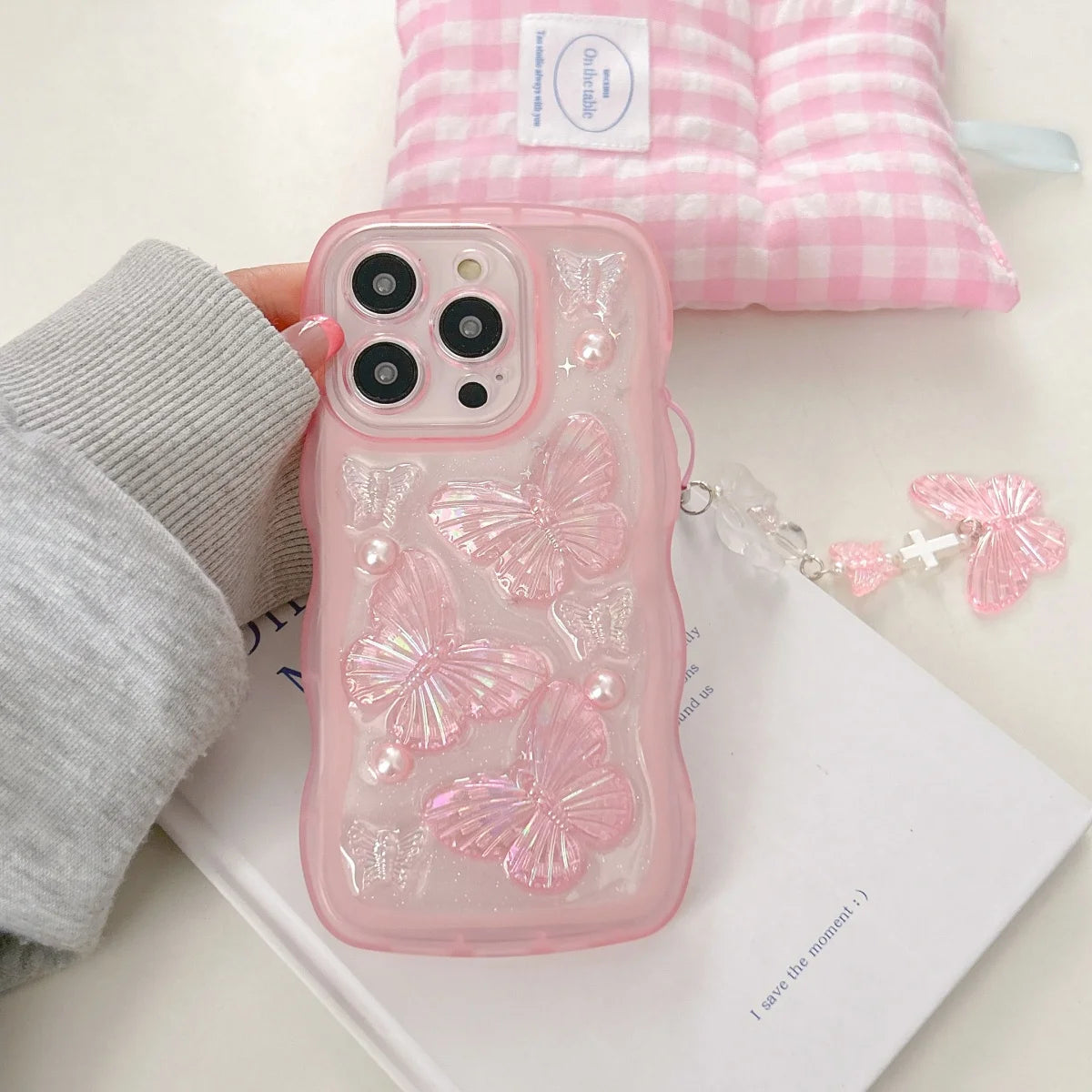 Pink phone case with kawaii butterfly design held by a hand on a light background