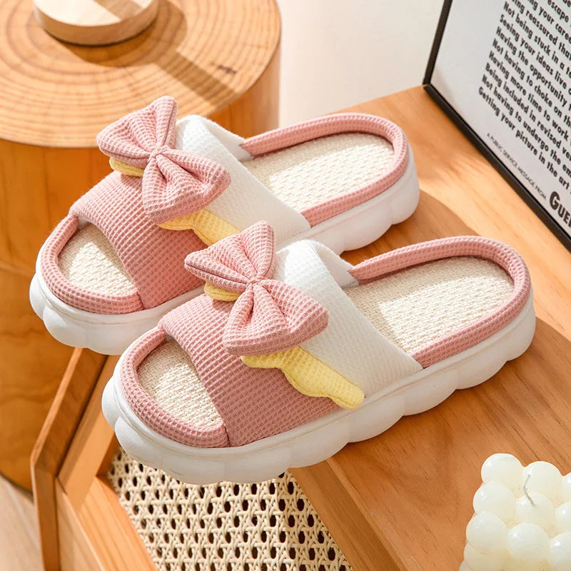 Pink kawaii slippers with bow details on a wooden surface