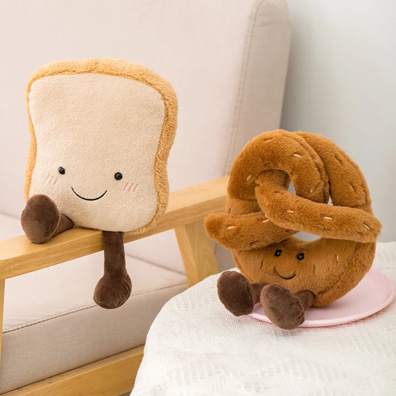Two plush kawaii toys shaped like a slice of bread and a pretzel on a light-colored couch.