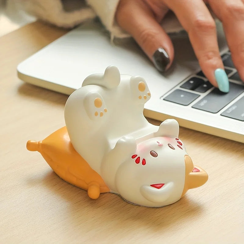 Cute animal-shaped kawaii desk accessory on a wooden surface with a laptop in the background.
