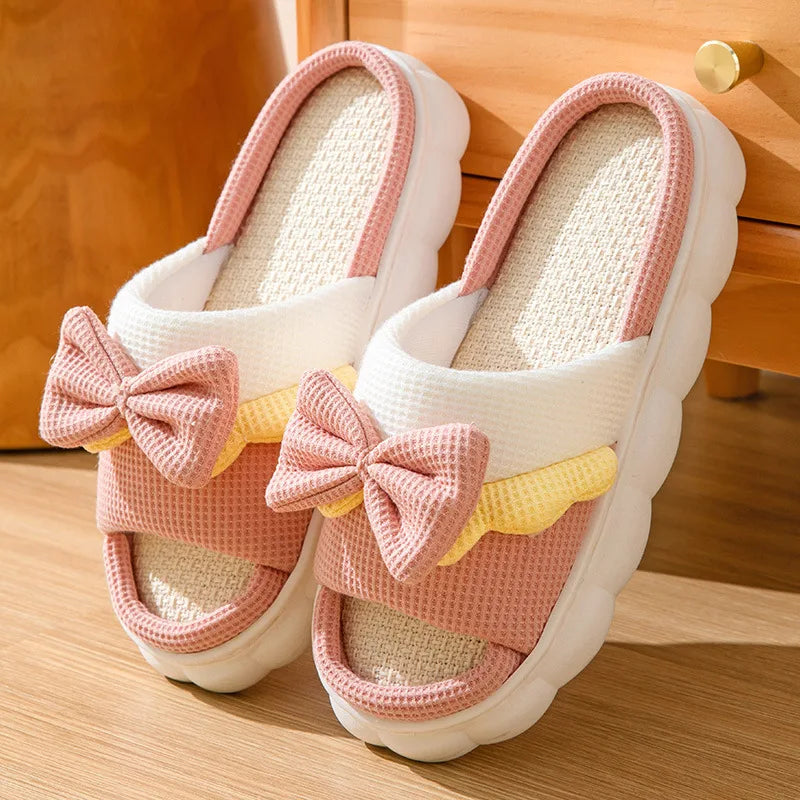White kawaii slippers with pink bows on a wooden floor