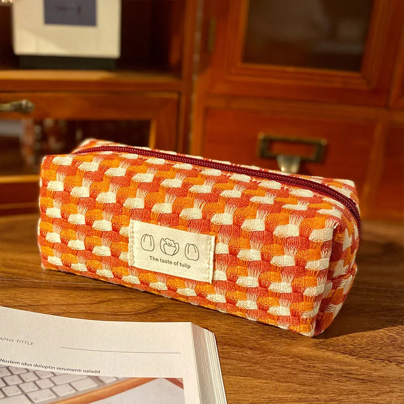 Orange and white checkered kawaii pouch with a label on a wooden surface