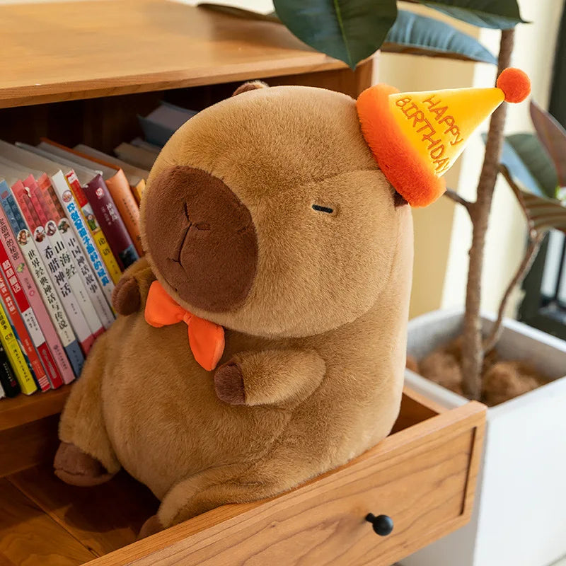 Kawaii plush toy elephant with a birthday hat on a wooden surface with books and a plant in the background