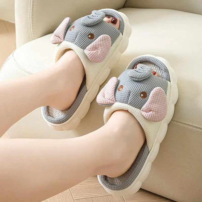 Children's kawaii cartoon slippers with elephant design on a beige couch.