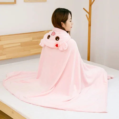 Person sitting on a bed wearing a pink kawaii cartoon character hooded blanket.