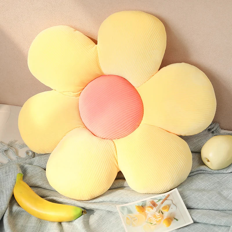 Flower-shaped Kawaii pillow with yellow petals and pink center on a soft surface