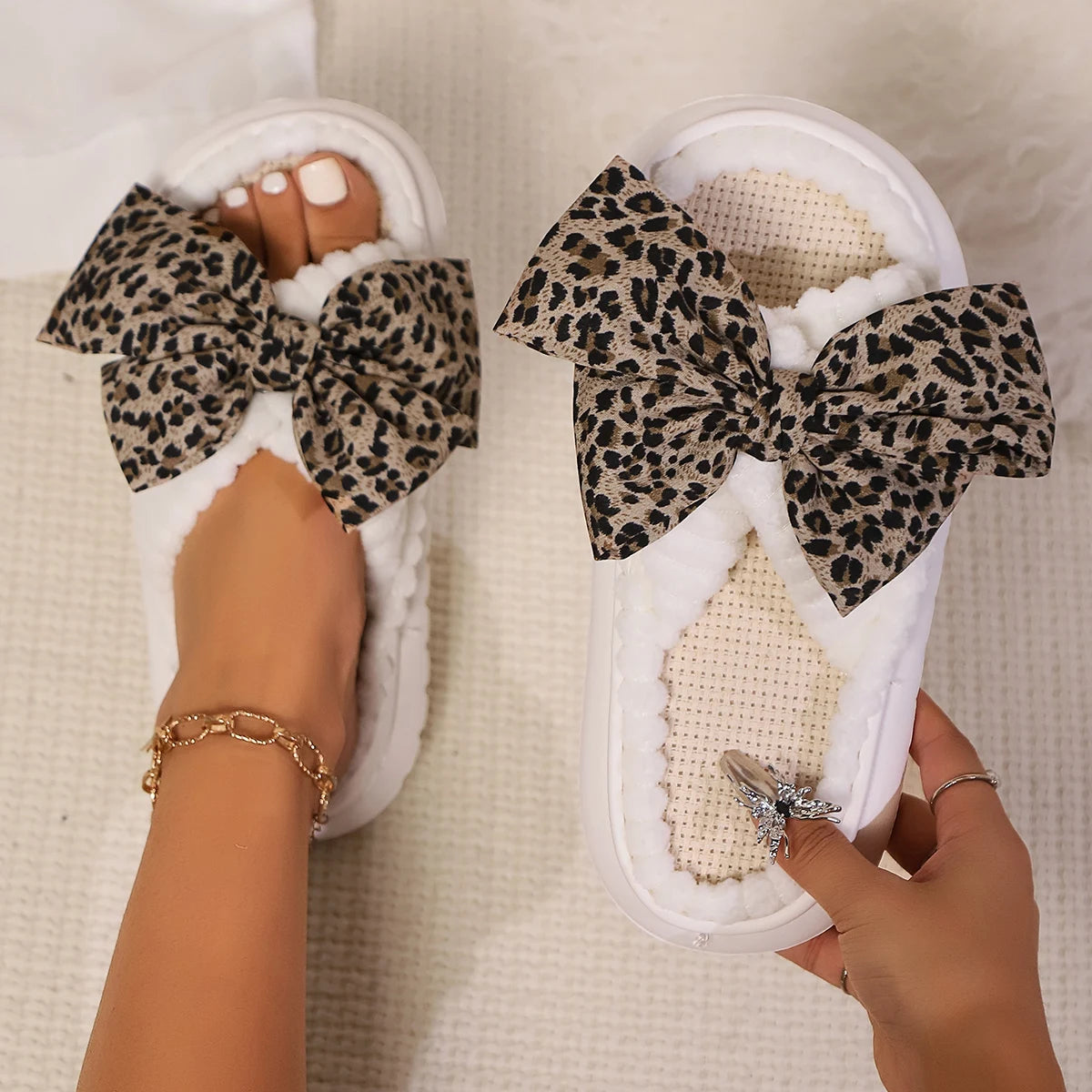 White slippers with leopard kawaii print bows worn by a person on a light background
