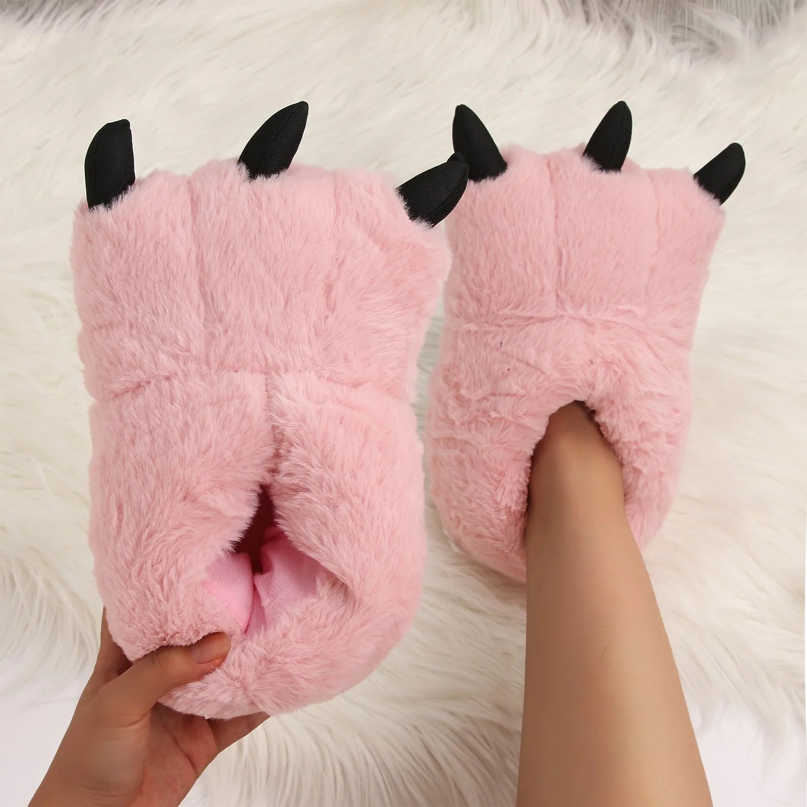 Pink kawaii slippers with black accents worn on a white fluffy surface