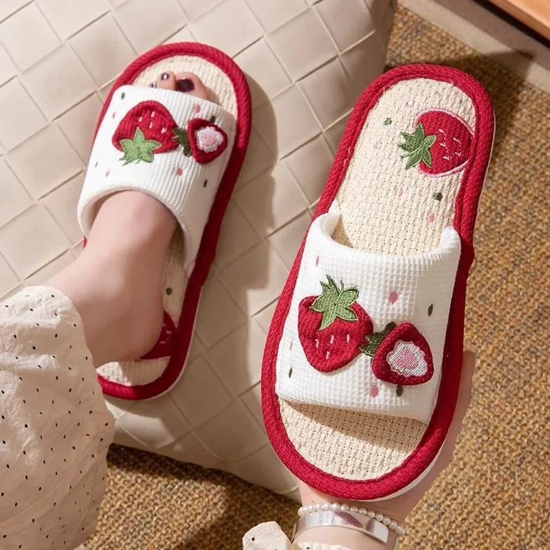 White slippers with red strawberry kawaii design on a tiled floor