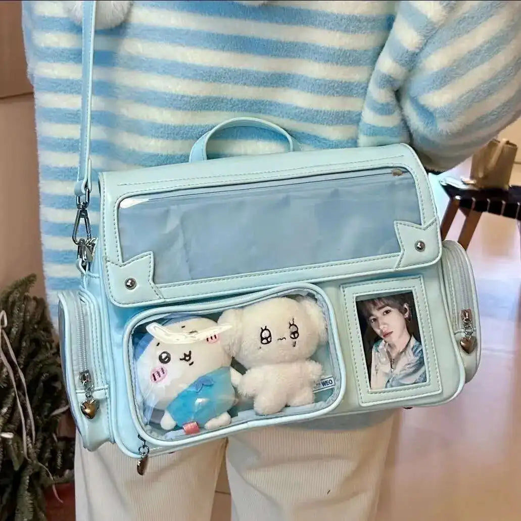 Light blue transparent bag with Kawaii plush toys and a photo inside, worn by a person in a striped sweater.