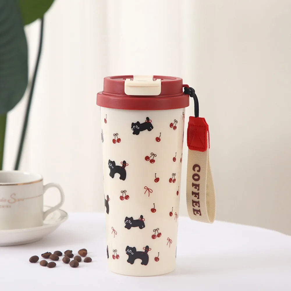 Travel mug with black cat and Kawaii cherry pattern on a white surface with a cup and coffee beans.