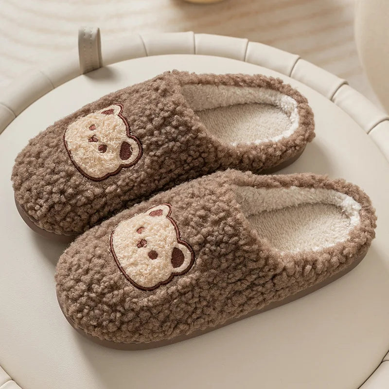 Pair of brown slippers with kawaii bear face designs on a light surface