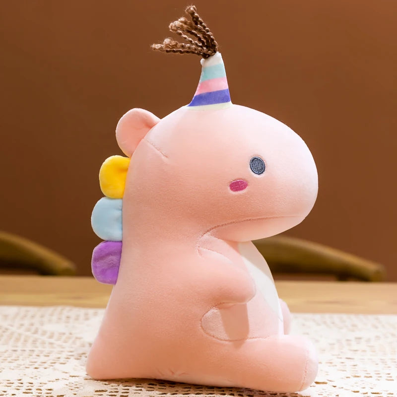 Pink kawaii plush toy with a rainbow-colored horn on a brown surface