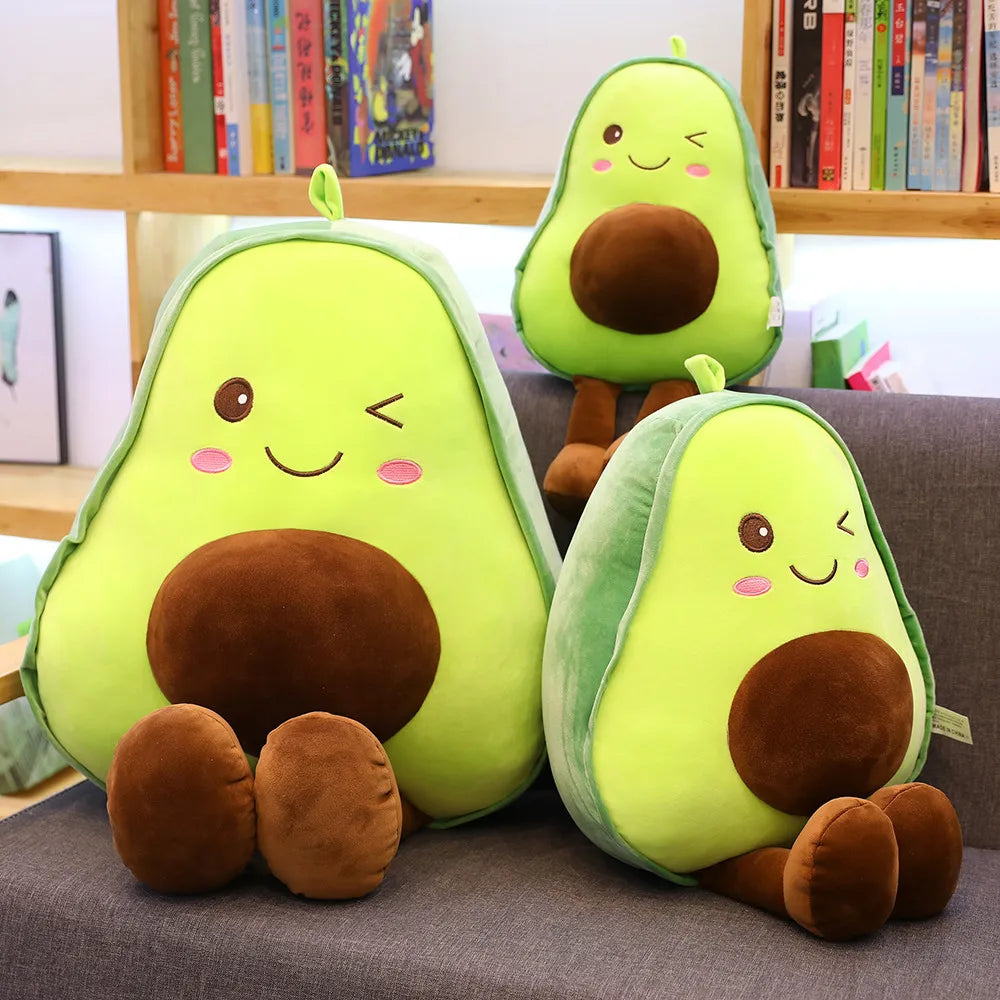 Three plush avocado kawaii toys on a couch with a bookshelf in the background