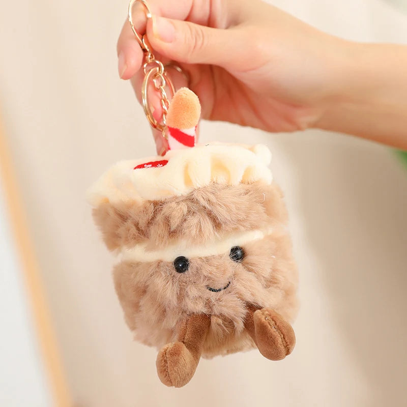 Plush keychain shaped like a kawaii bear with a straw in its mouth, held by a hand against a neutral background.