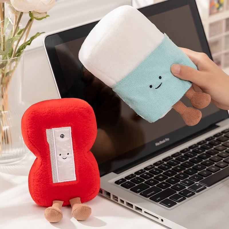 Two kawaii plush toys, one red and one blue, sitting on a laptop.