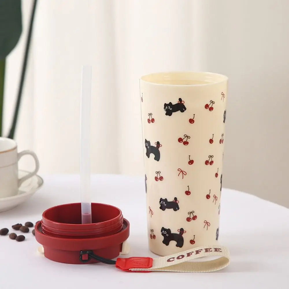 Collapsible red coffee cup with beige sleeve featuring black dog and Kawaii cherry pattern on a white surface.