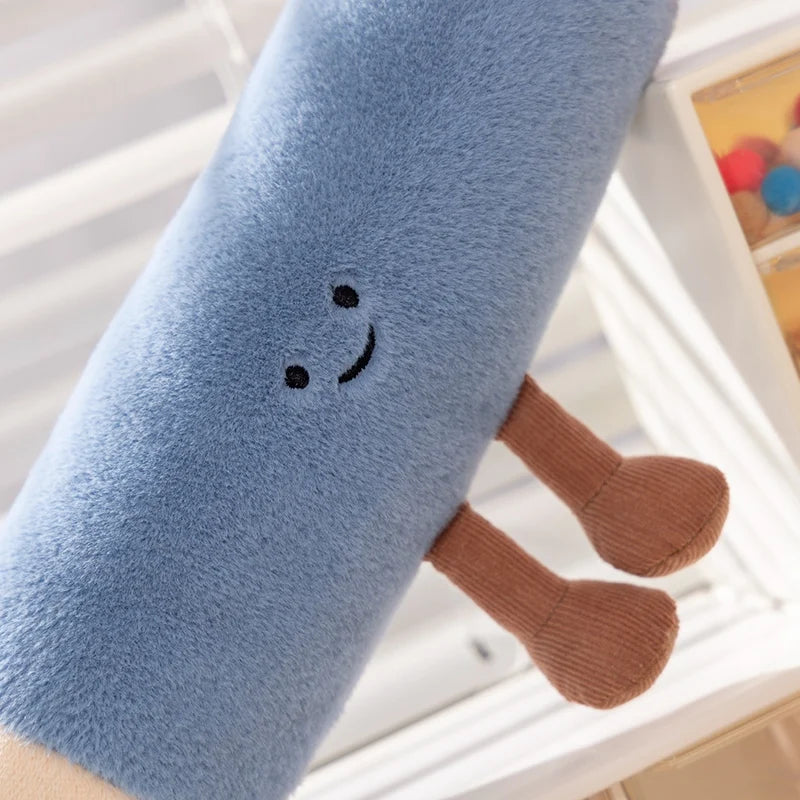 Blue kawaii plush toy with a smiley face and brown legs on a light wooden surface.