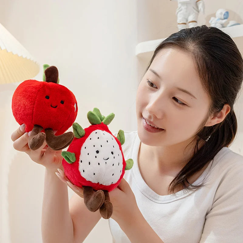 Woman holding two plush kawaii toys shaped like a red apple and a strawberry.