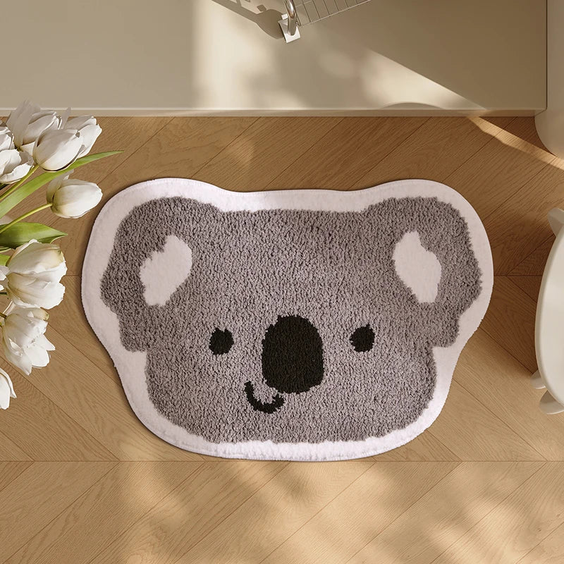 Gray koala-shaped kawaii rug on a wooden floor with white tulips.