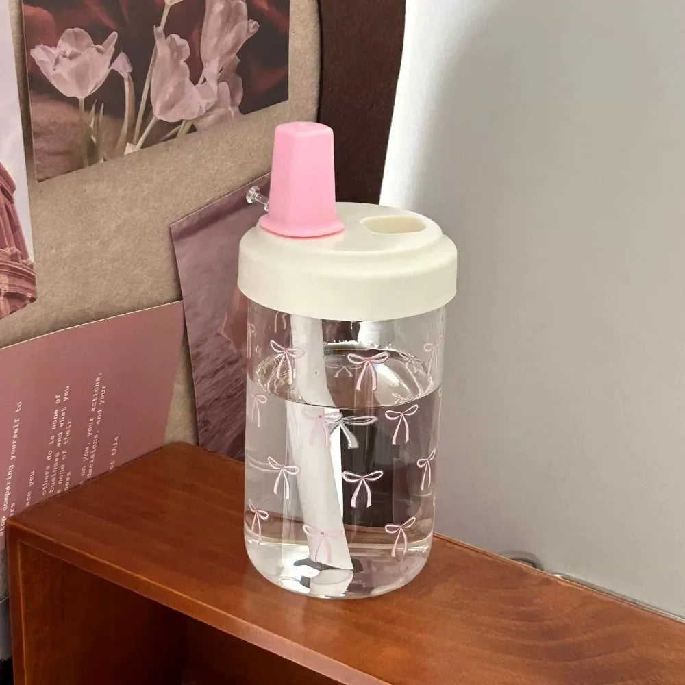 Clear Kawaii water bottle with pink cap on a wooden surface