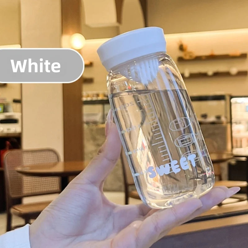 Clear Kawaii water bottle with white cap held in a hand, blurred indoor background
