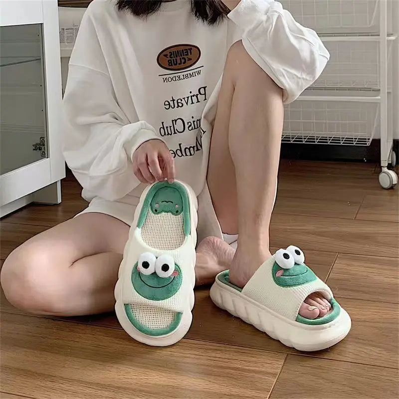 Person wearing kawaii cartoonish green and white slippers with frog design on a wooden floor.