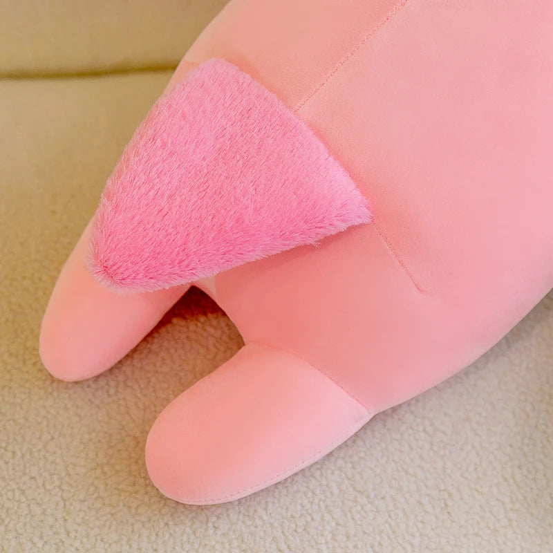 Pink kawaii plush toy on a finger against a beige background