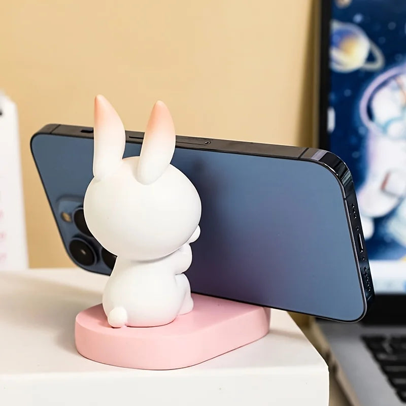 White rabbit kawaii phone holder on a pink base with a smartphone on a desk.