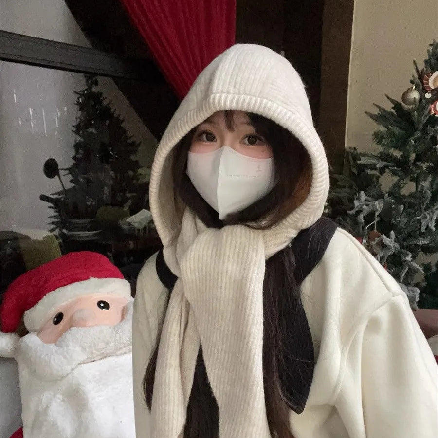 Person wearing a Kawaii white hooded outfit with a face mask, standing next to a plush toy in a festive setting.